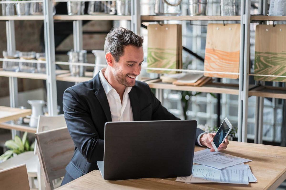 Business Direct connect man at computer Happy business man working at a restaurant using a laptop computer and smiling