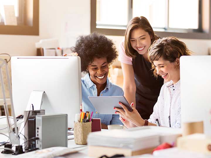 Happy businesswomen using digital tablet in office