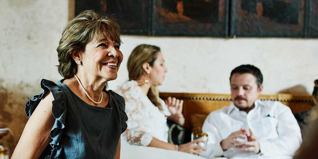 Smiling grandmother sitting in living room with in-laws and children before dinner party